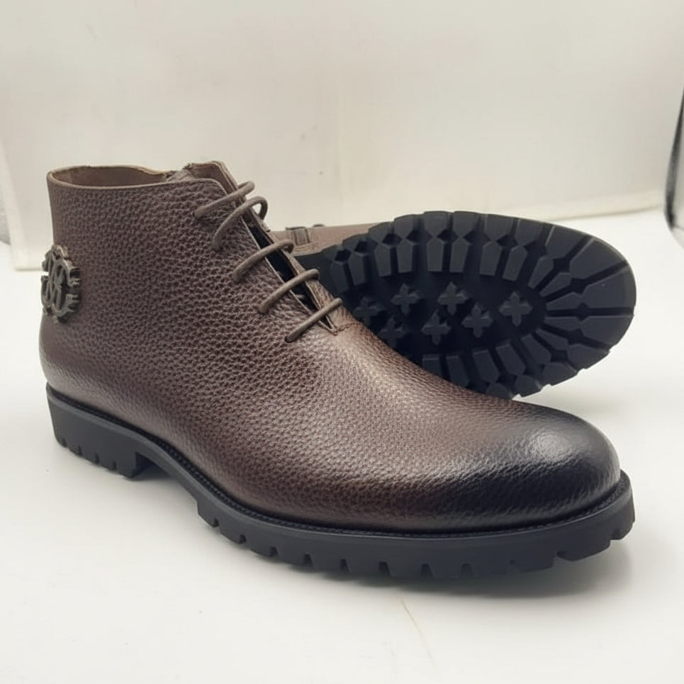 Rich espresso brown pebbled leather upper with dark metal emblem and rugged lug outsole